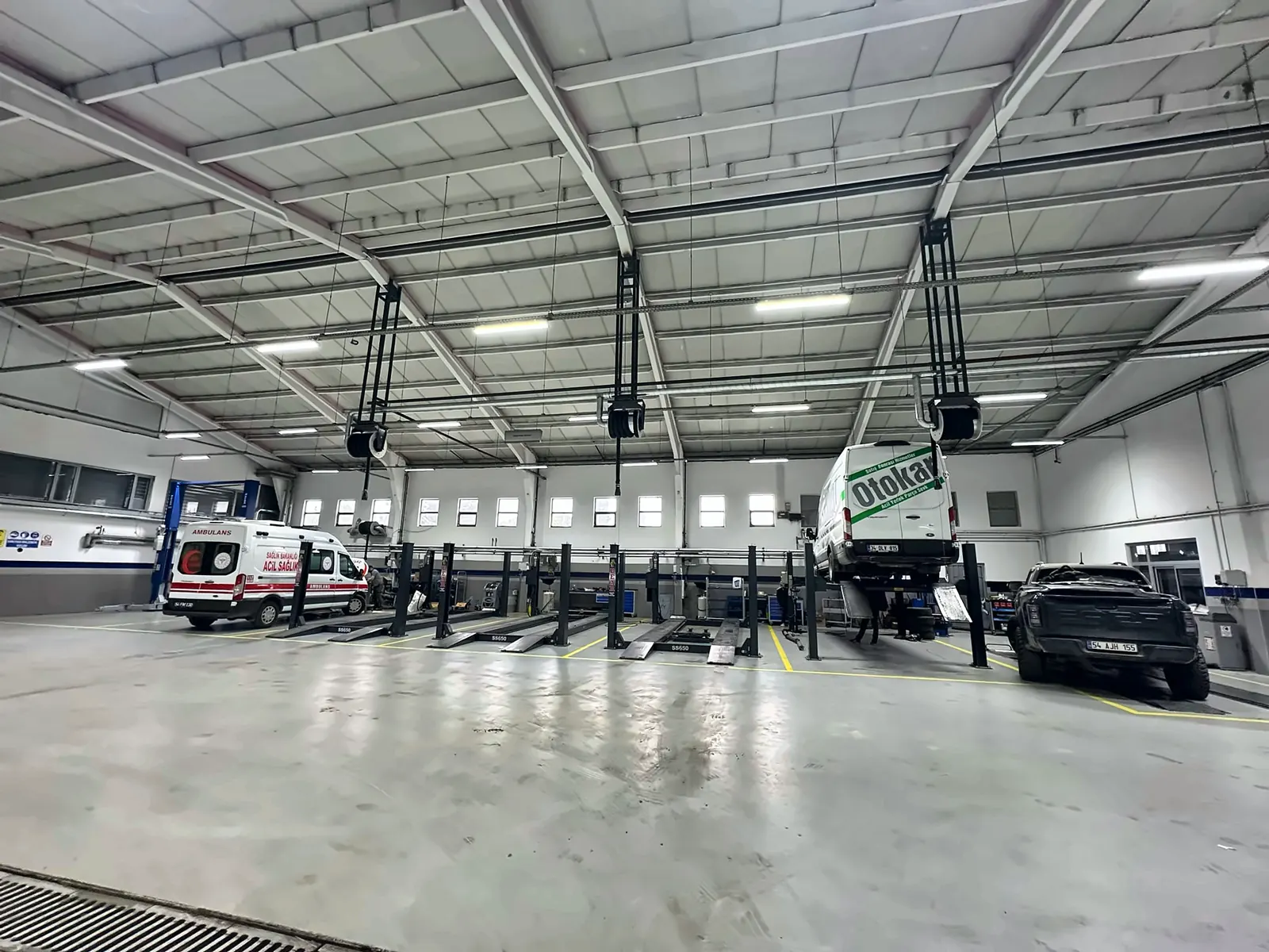 Geniş servis atölyesinde tavan konstrüksiyonuna monteli egzoz makaraları