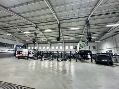Geniş servis atölyesinde tavan konstrüksiyonuna monteli egzoz makaraları