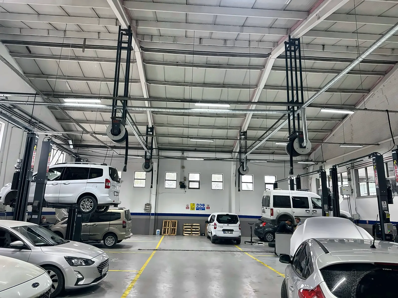 Çelik çatılı atölyede lift başlarına inen egzoz gazı tahliye hortumları